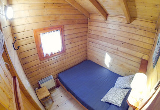 Knusse houten slaapkamer met tweepersoonsbed in Bungalow Comfort bij Camping Bedura Park, Spanje.