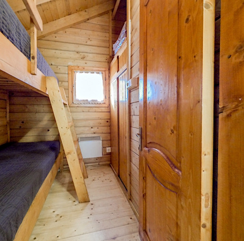 Wood-paneled bunk bed room in Bungalow Comfort at Campsite Bedura Park, Spain, with natural lighting.