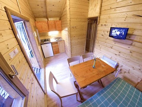 Interior del bungalow Zen en el camping Bedura Park en España, cocina pequeña y comedor de madera.