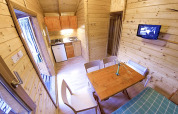 Interior del bungalow Zen en el camping Bedura Park en España, cocina pequeña y comedor de madera.