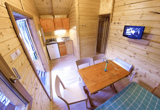 Interior of Bungalow Zen at Campsite Bedura Park in Spain, featuring wooden walls, dining and kitchenette.