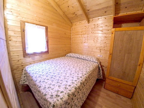 Wood-paneled bedroom in Bungalow Zen at Campsite Bedura Park, Spain, featuring a double bed and wardrobe.
