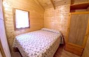 Camera da letto in legno del Bungalow Zen al campeggio Bedura Park, Spagna, con letto matrimoniale.