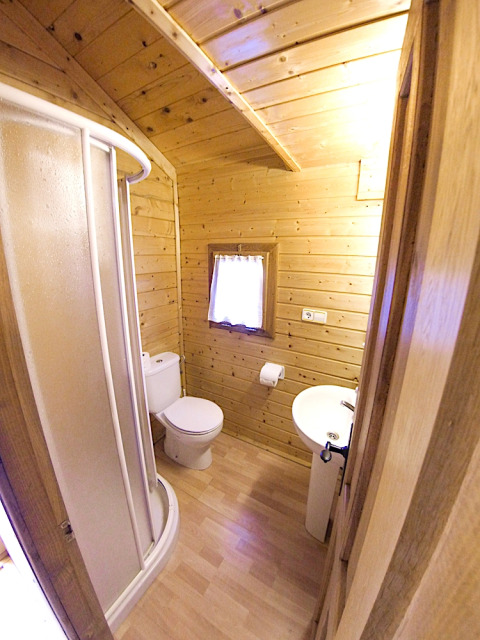 Compact bathroom with wood walls at Bungalow “Zen”, Campsite Bedura Park, Spain. Includes shower and toilet.