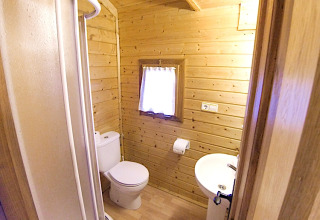 Compact bathroom with wood walls at Bungalow “Zen”, Campsite Bedura Park, Spain. Includes shower and toilet.