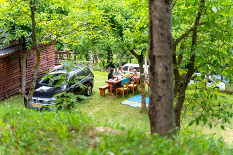 Outdoor gathering at Bungalow «Zen», Bedura Park Campsite, Spain, with people eating by a wooden cabin.