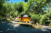 Chalet en bois entouré d’arbres verts et de soleil au Camping Bedura Park, Espagne, lors d’une journée paisible.
