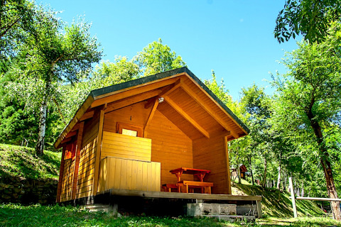 Et hyggeligt træhus kaldet Cabin ved Campsite Bedura Park i Spanien, omgivet af grønne træer og solskin.