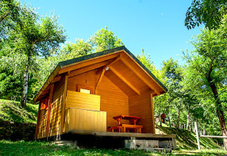 Acogedora cabaña de madera llamada Cabin en el Campsite Bedura Park en España, rodeada de árboles verdes.