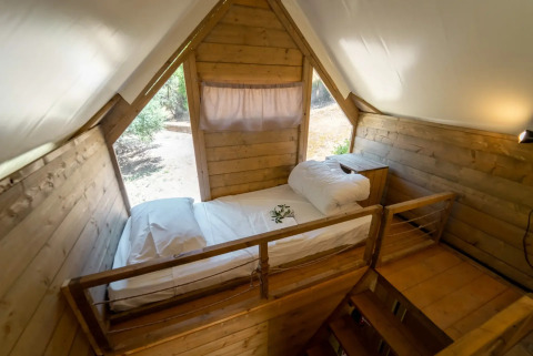 Indvendigt billede af en hyggelig træseng på hems i et safari-telt ved Vallicella Glamping Resort, Italien.