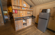 Coin cuisine de la Safari Lodge 1 au Vallicella Glamping Resort, bois, réfrigérateur et micro-ondes visibles.