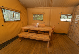 Intérieur du Safari Lodge 1 au Vallicella Glamping Resort en Italie, avec table et bancs en bois.
