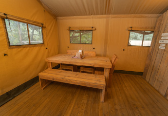 Indretning af Safari Lodge 1 i Vallicella Glamping Resort, Italien med træbord og bænke.