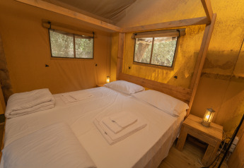 Indvendig udsigt over et hyggeligt soveværelse i Safari Lodge 1, Vallicella Glamping Resort, Italien.