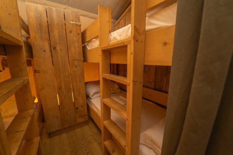 Lits superposés en bois dans la tente Safari Lodge 1 au Vallicella Glamping Resort en Italie, ambiance chaleureuse.