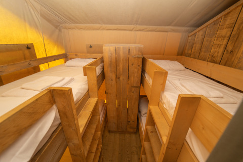 Intérieur de la Safari Lodge 1 avec quatre lits superposés en bois au Vallicella Glamping Resort, Italie.