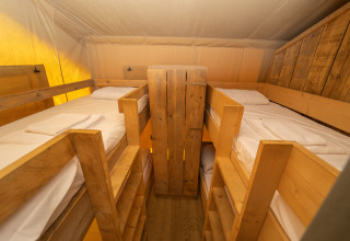 Intérieur de la Safari Lodge 1 avec quatre lits superposés en bois au Vallicella Glamping Resort, Italie.