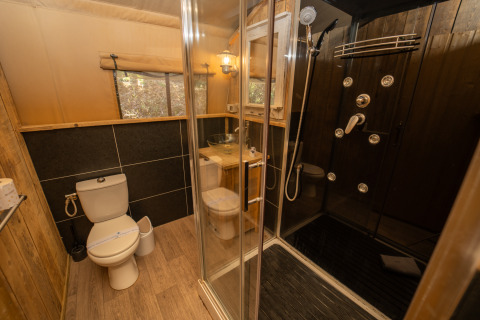 Salle de bain moderne à Safari Lodge 1, Vallicella Glamping Resort, Italie, avec douche et décor en bois.