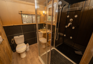 Salle de bain moderne à Safari Lodge 1, Vallicella Glamping Resort, Italie, avec douche et décor en bois.