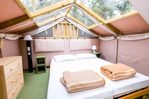 Binnenzicht van een Air Lodge safaritent in Vallicella Glamping Resort, Italië, met een tweepersoonsbed.