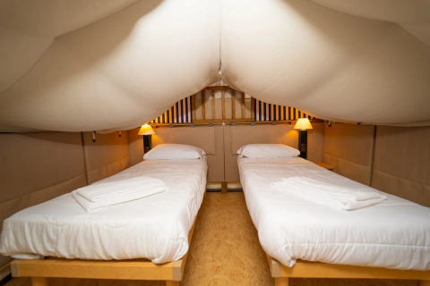 Binnen in een safaritent met twee eenpersoonsbedden bij Vallicella Glamping Resort in Italië.