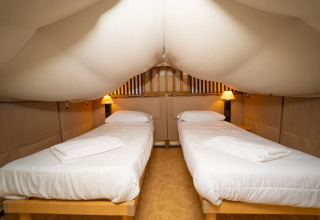 Binnen in een safaritent met twee eenpersoonsbedden bij Vallicella Glamping Resort in Italië.
