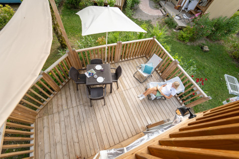 Luchtfoto van een houten terras met tuinset en een relaxte gast bij Air Lodge glamping verblijf.