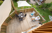 Luchtfoto van een houten terras met tuinset en een relaxte gast bij Air Lodge glamping verblijf.