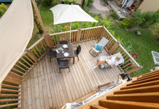 Luchtfoto van een houten terras met tuinset en een relaxte gast bij Air Lodge glamping verblijf.