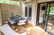 Terrasse en bois avec table à manger et chaises de Cottage Next L, Vallicella Glamping Resort, Italie, vue nature.
