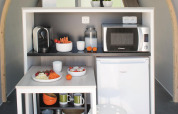 Petite kitchenette et table de repas dans une tente safari au Vallicella Glamping Resort, Italie, avec micro-ondes.