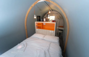 Intérieur du logement glamping Coco Couple avec lit double, déco moderne et ambiance chaleureuse.