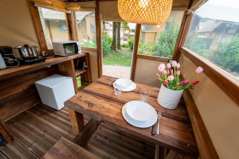Intérieur chaleureux d’une tente safari équipée d’une cuisine en bois à l’Air Stay XL, Vallicella Glamping Resort, Italie.
