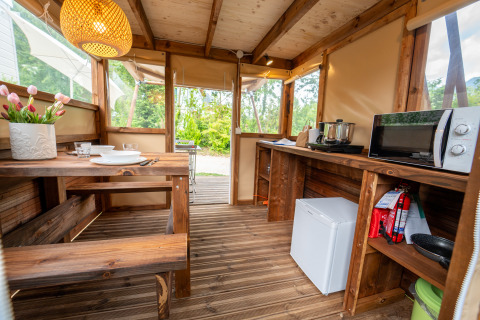 Intérieur de la tente safari « Air Stay » XL au Vallicella Glamping Resort en Italie, avec table et kitchenette.