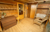 Intérieur en bois d'une tente safari avec commode, chaise en osier et étagères au Vallicella Glamping Resort, Italie.