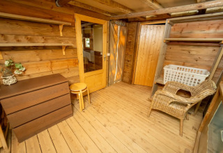 Holzinterieur eines Safarizelts mit Kommode, Korbstuhl und Regalen im Vallicella Glamping Resort, Italien.