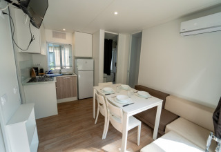 Hébergement glamping moderne avec kitchenette, table à manger, canapé, climatisation et télévision.