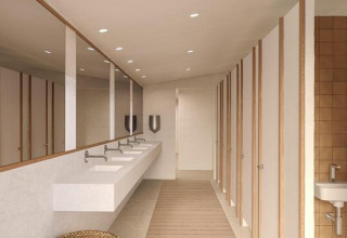 Baño moderno de tienda safari con suelo de madera, lavabos, espejos, puertas y cesta de mimbre.