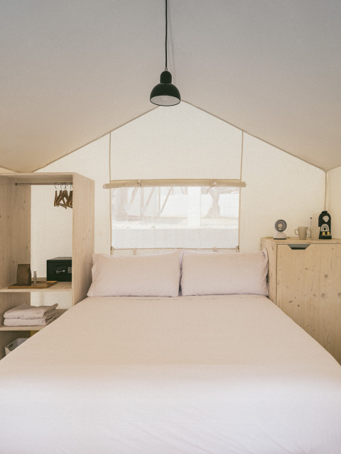 Vista interna della Cottage Couple Tent al Wecamp Cadaqués in Spagna con letto matrimoniale e arredo semplice.