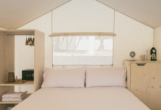 Vista interna della Cottage Couple Tent al Wecamp Cadaqués in Spagna con letto matrimoniale e arredo semplice.
