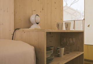 Interno della Cottage Family Tent al Wecamp Cadaqués, Spagna, con scaffale in legno e stoviglie visibili.