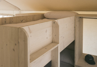 Letti a castello e scaffali in legno in una tenda safari chiamata «Cottage Family Tent» a Wecamp Cadaqués, Spagna.