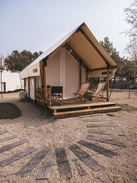 Safaritent bij Wecamp Cadaqués in Spanje met houten terras, ligstoelen en grindpad erboven.