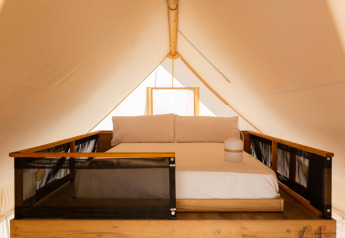 Letto matrimoniale su soppalco in tenda safari Glamping Family Plus presso Wecamp Cadaqués, Spagna.