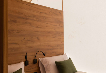 Letti singoli con cuscini verdi in una moderna tenda safari al Glamping Family Plus, Wecamp Cadaqués, Spagna.
