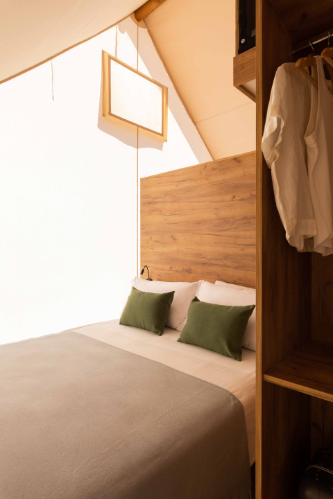 Binnenzicht in een Glamping Family Plus safaritent bij Wecamp Cadaqués, Spanje, met een sfeervol bed.
