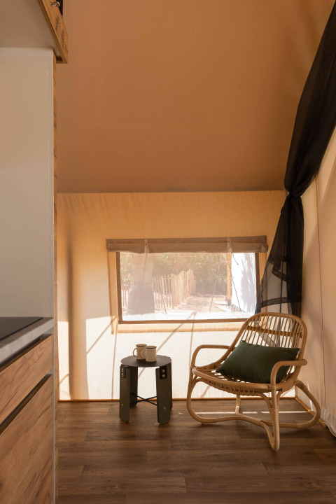 Interieur van de Glamping Family Plus safaritent bij Wecamp Cadaqués met een stoel en veel zonlicht.