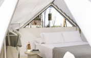 Innenansicht des Bell Tent Glamping mit Doppelbett, Nachttisch, Lampe und Kleiderständer.