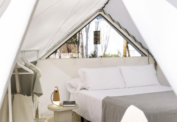 Vue intérieure du glamping Bell Tent avec lit double, table de chevet, lampe et portemanteau.