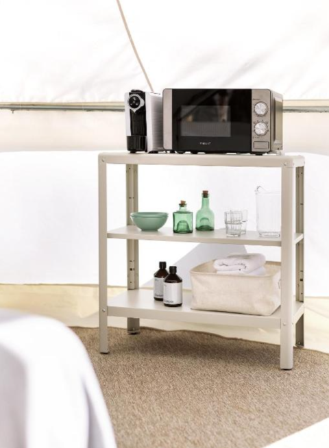 Foto di un alloggio glamping con scaffale bianco, microonde, macchina da caffè e bottiglie.
